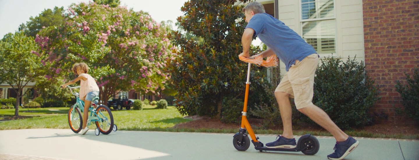 Child riding bike, adult riding scooter