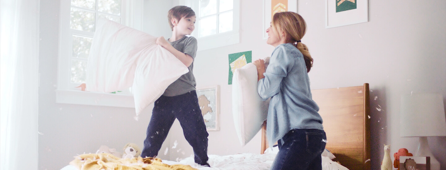 Child and adult having a pillow fight in bedroom